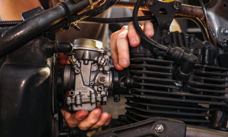a person’s hands on the carburetor of a motorcycle